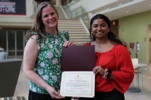 Two women holding award.